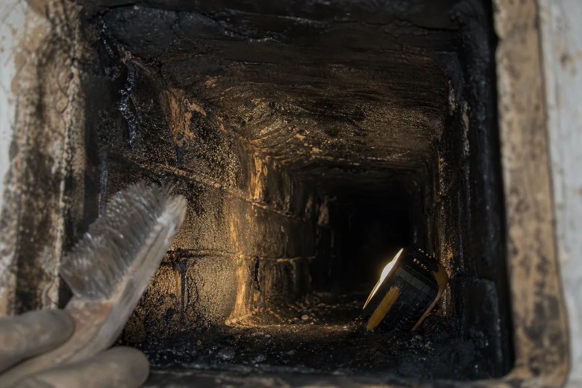 Dépôts de bistre goudronneux dans un conduit ancien en brique foraine avant débistrage mécanique